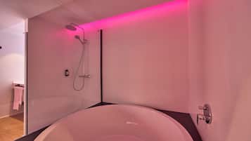 A modern bathroom with a freestanding bathtub, a showerhead, and a towel rack.