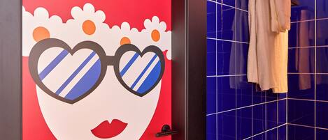 Un baño con pared roja, pared con azulejos azules y un perchero con toallas.