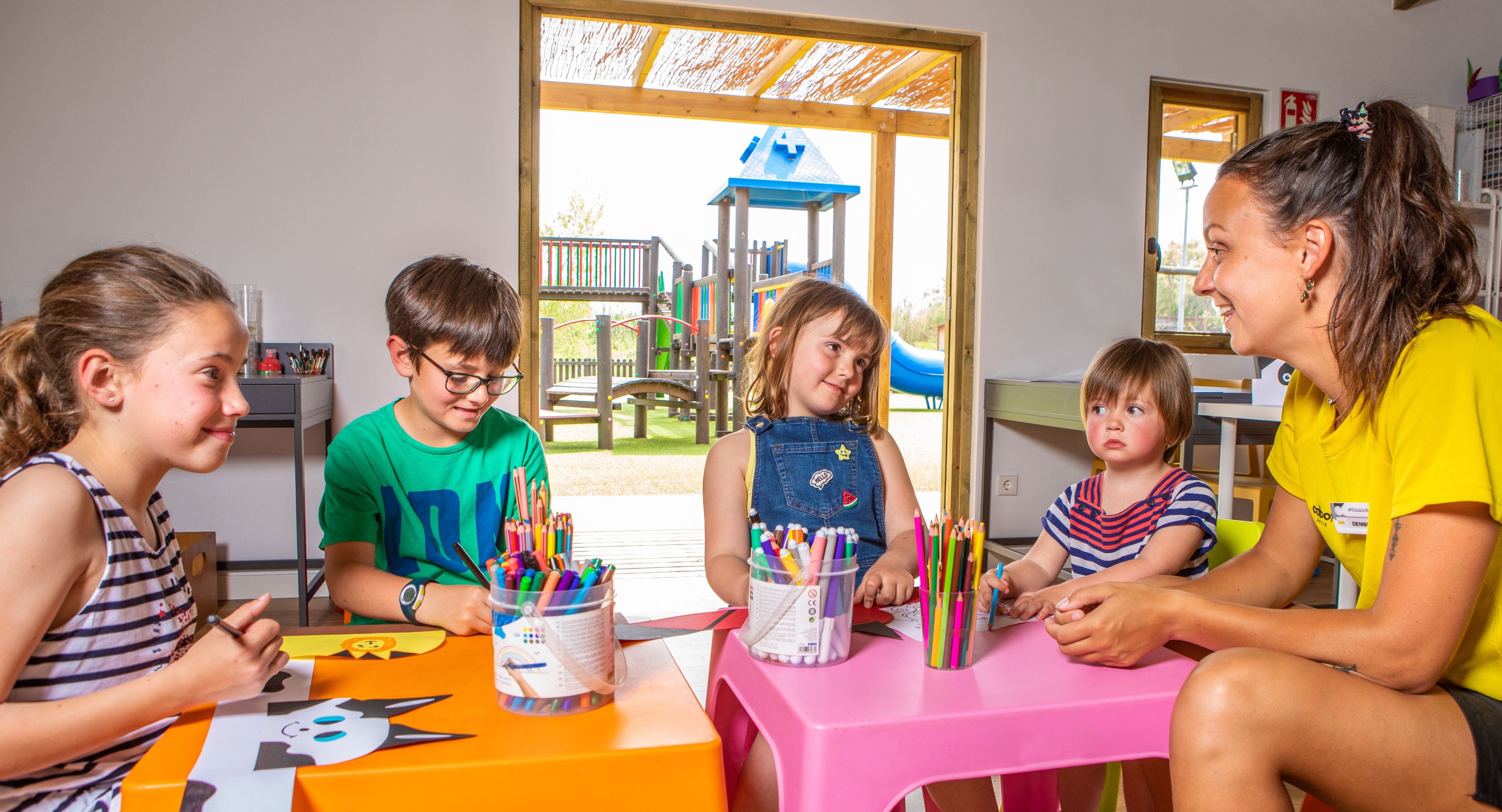 Eine Gruppe von Kindern und ein Erwachsener sitzen an einem Tisch mit Malutensilien.