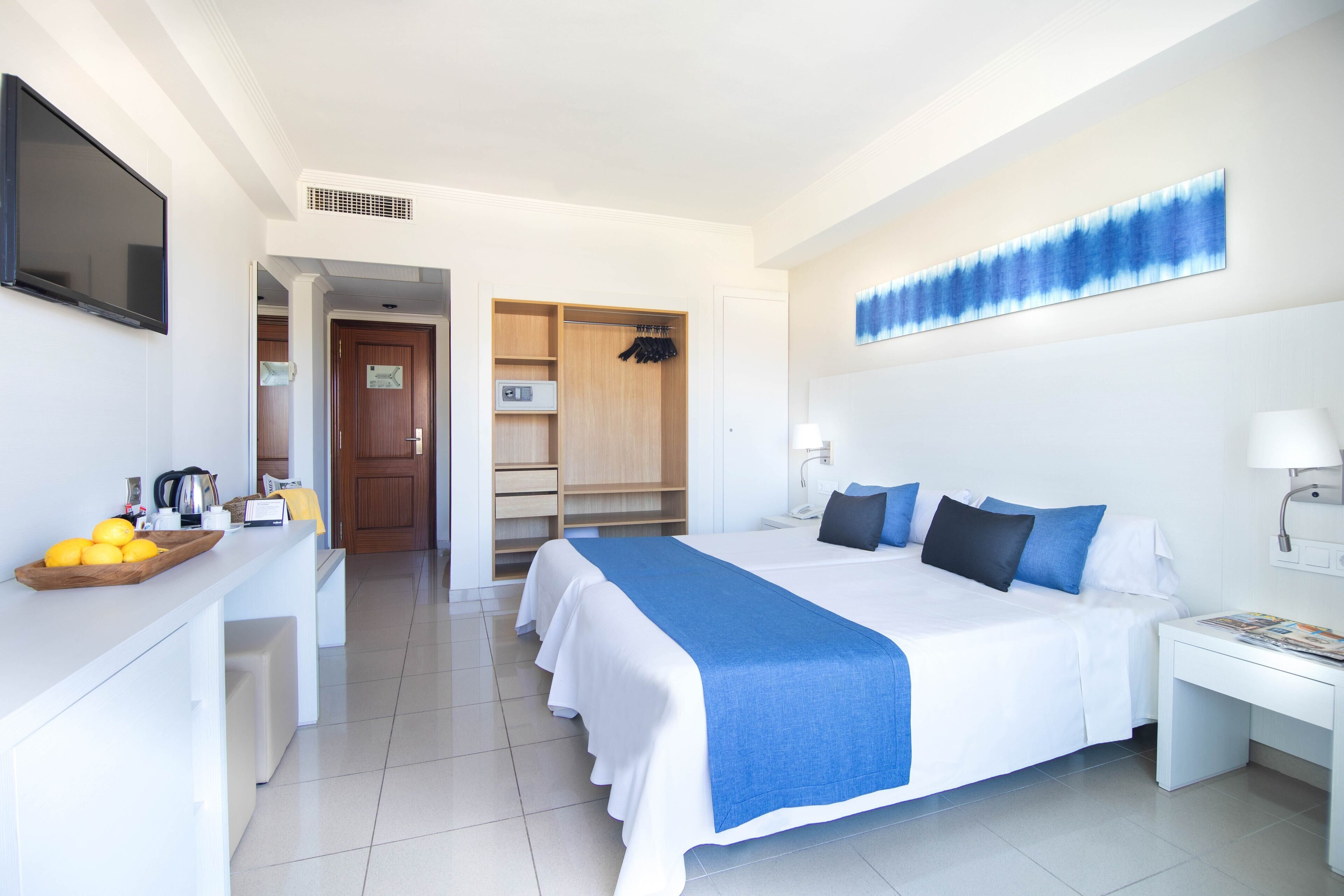 Une chambre d’hôtel avec un grand lit, un bureau, une chaise, une télévision et une armoire.