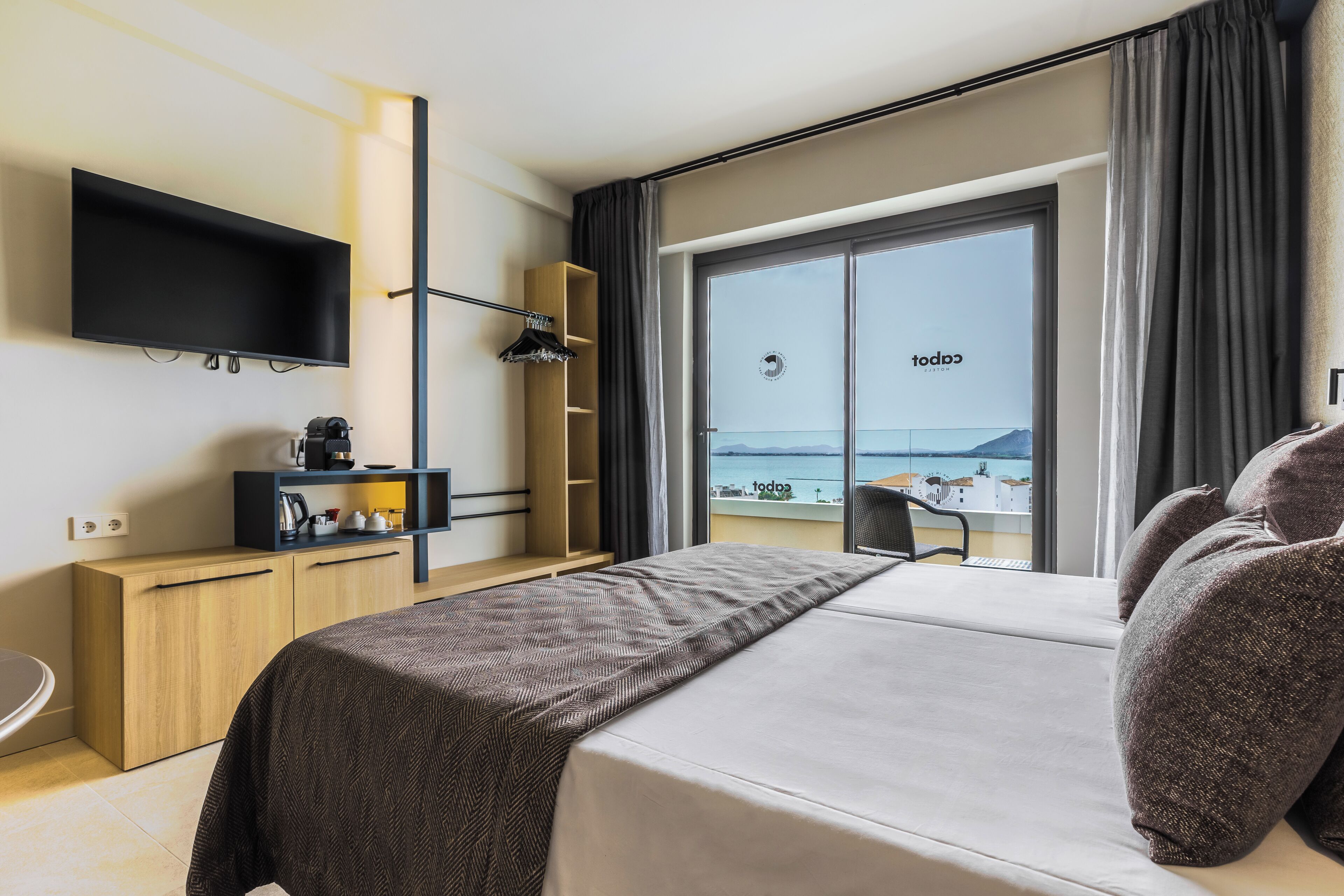 Habitación de hotel moderna con una cama grande, un televisor de pantalla plana, un escritorio y vistas al mar.