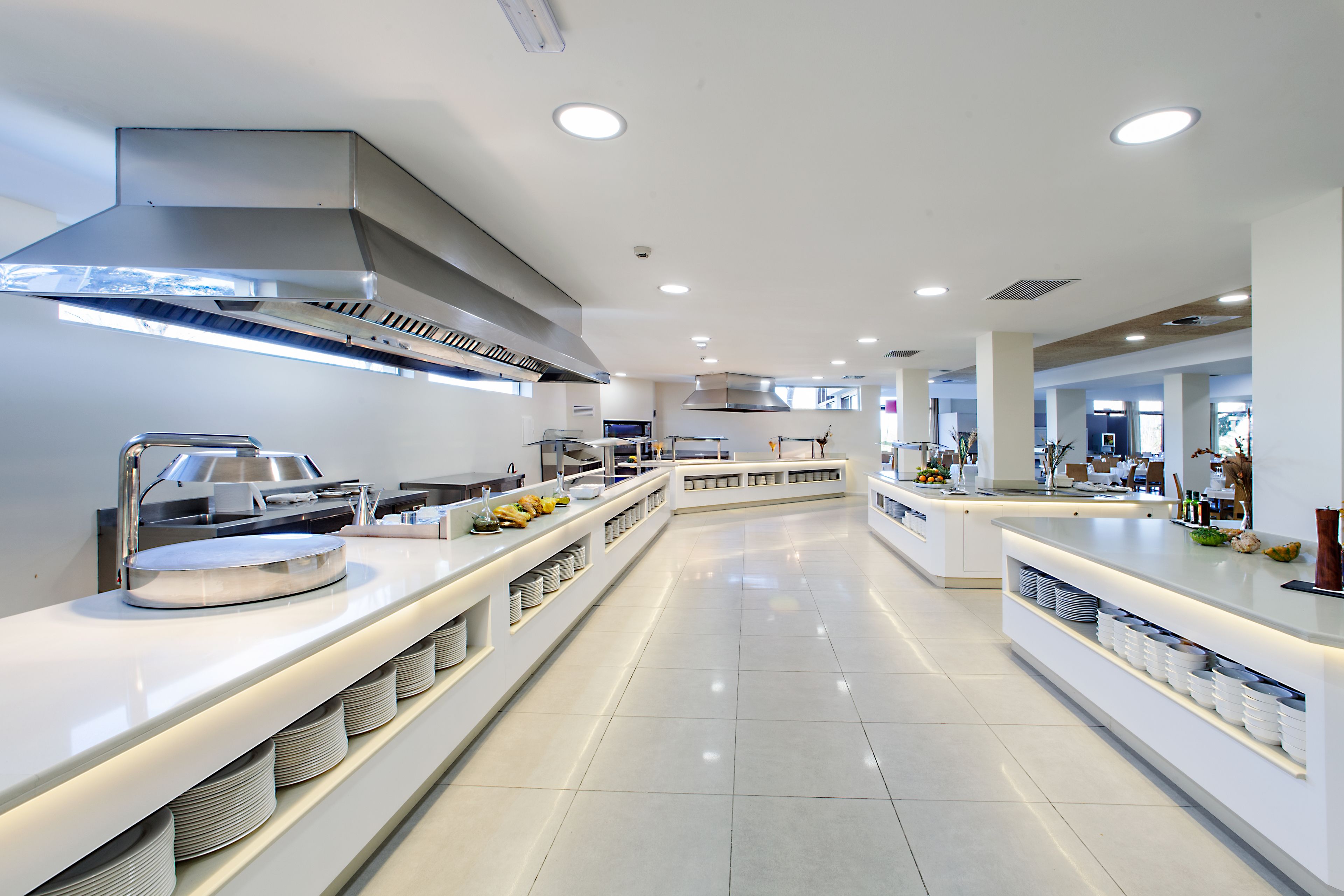 A modern kitchen with stainless steel appliances, white countertops, and a central island with seating.