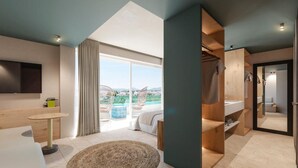 A modern hotel room with a large window, a bed, a TV, a small table, and a walk-in closet. - Cabot Pollensa Park Spa - Family Resort (Pollenca)