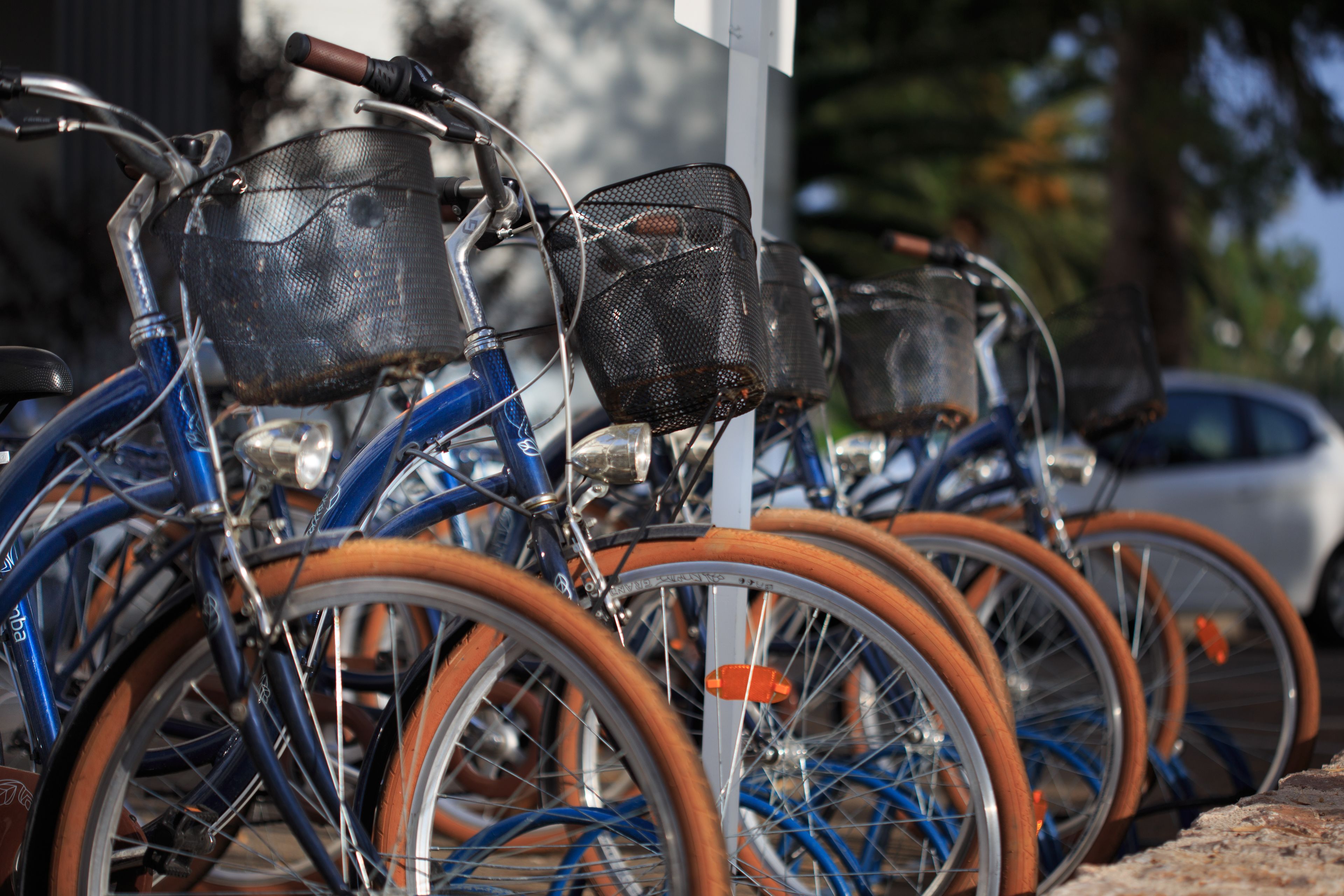 A row of bicycles with baskets, parked in a line.
