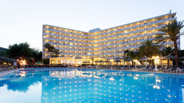 A large hotel with a swimming pool, multiple balconies, and palm trees. - Cabot Pollensa Park Spa - Family Resort (Pollenca)