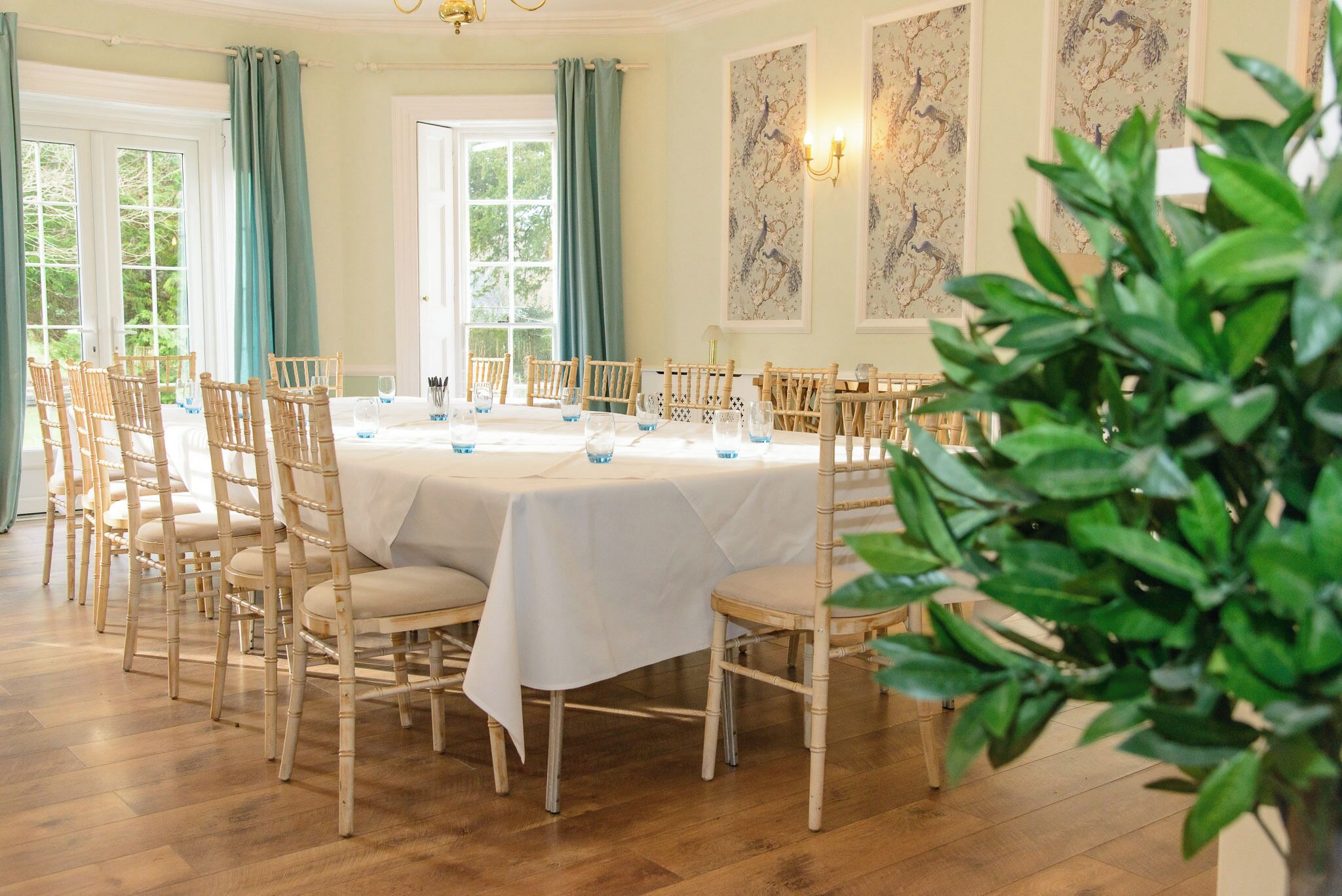 A dining area with a round table, wooden chairs, and a white tablecloth.