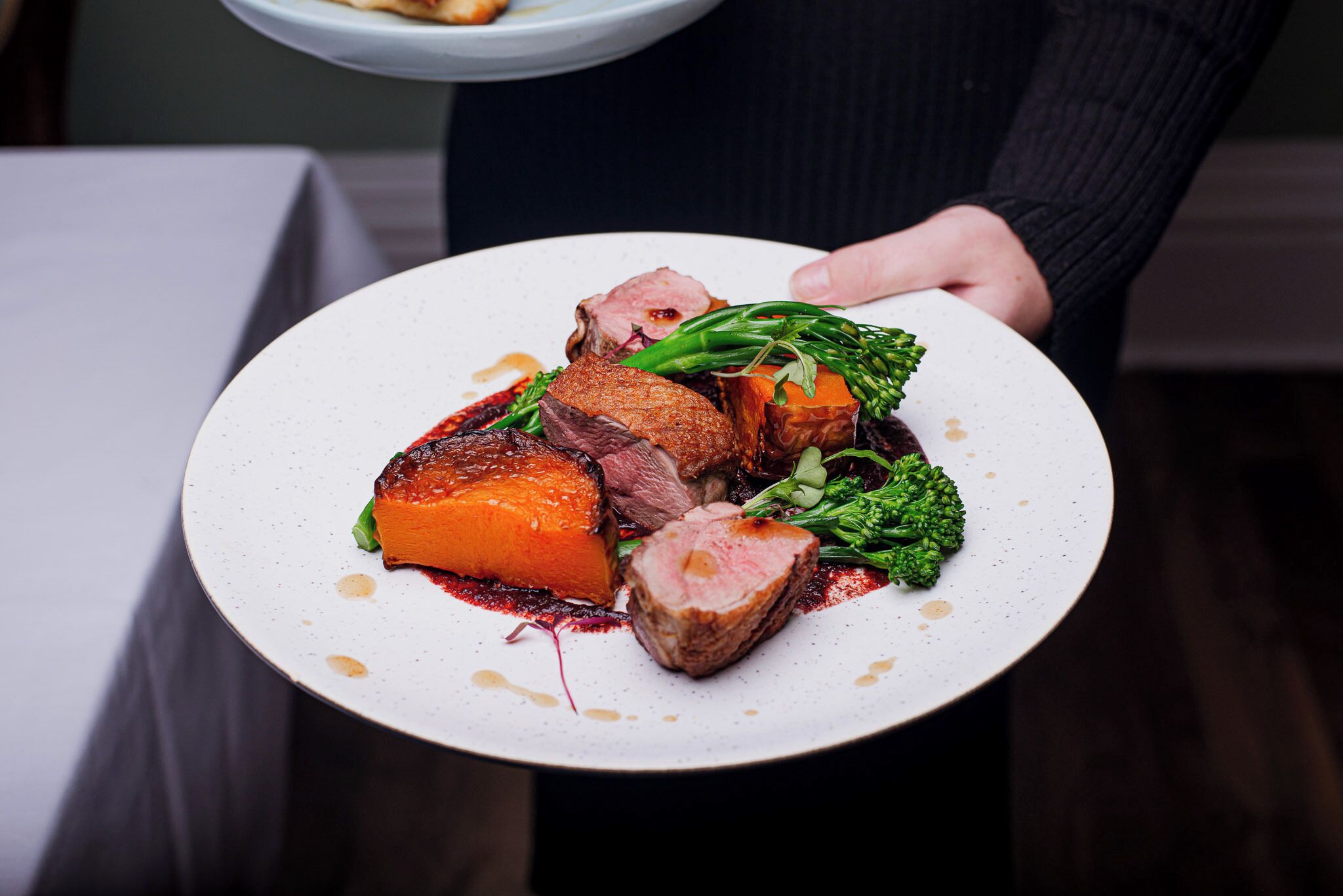 A person holding a plate with various food items.