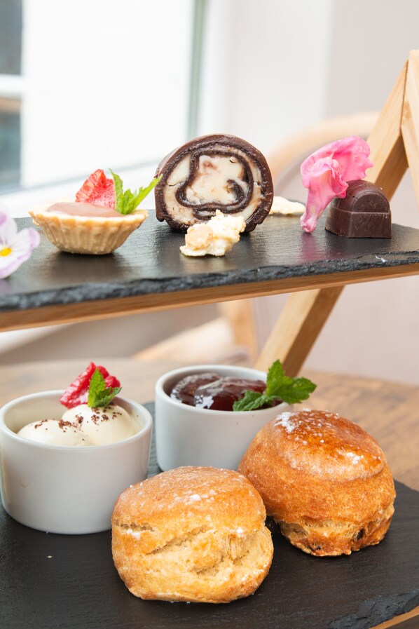 Una mesa de postres con varios pasteles y dulces, incluyendo un pastel enrollado, una tarta y una barra de chocolate.