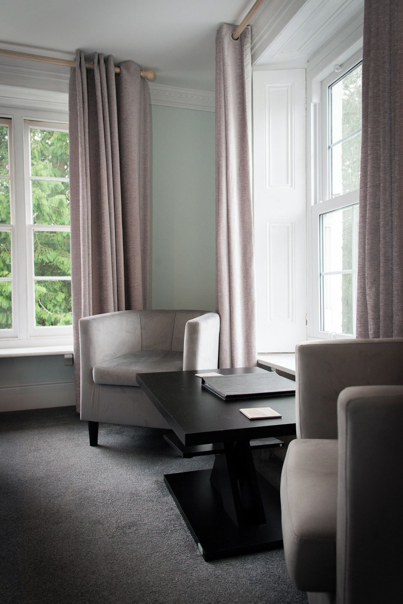 A modern room with a sofa, a table, and a view of greenery outside.