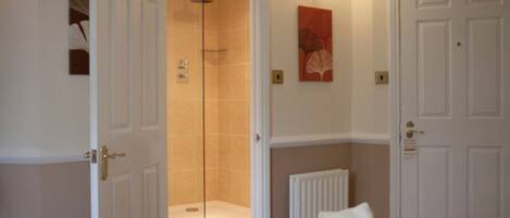 A hotel room with a bed, a shower, and a door.