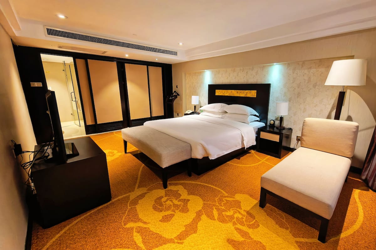 Een hotelkamer met een bed, nachtkastje, stoel en een televisie.