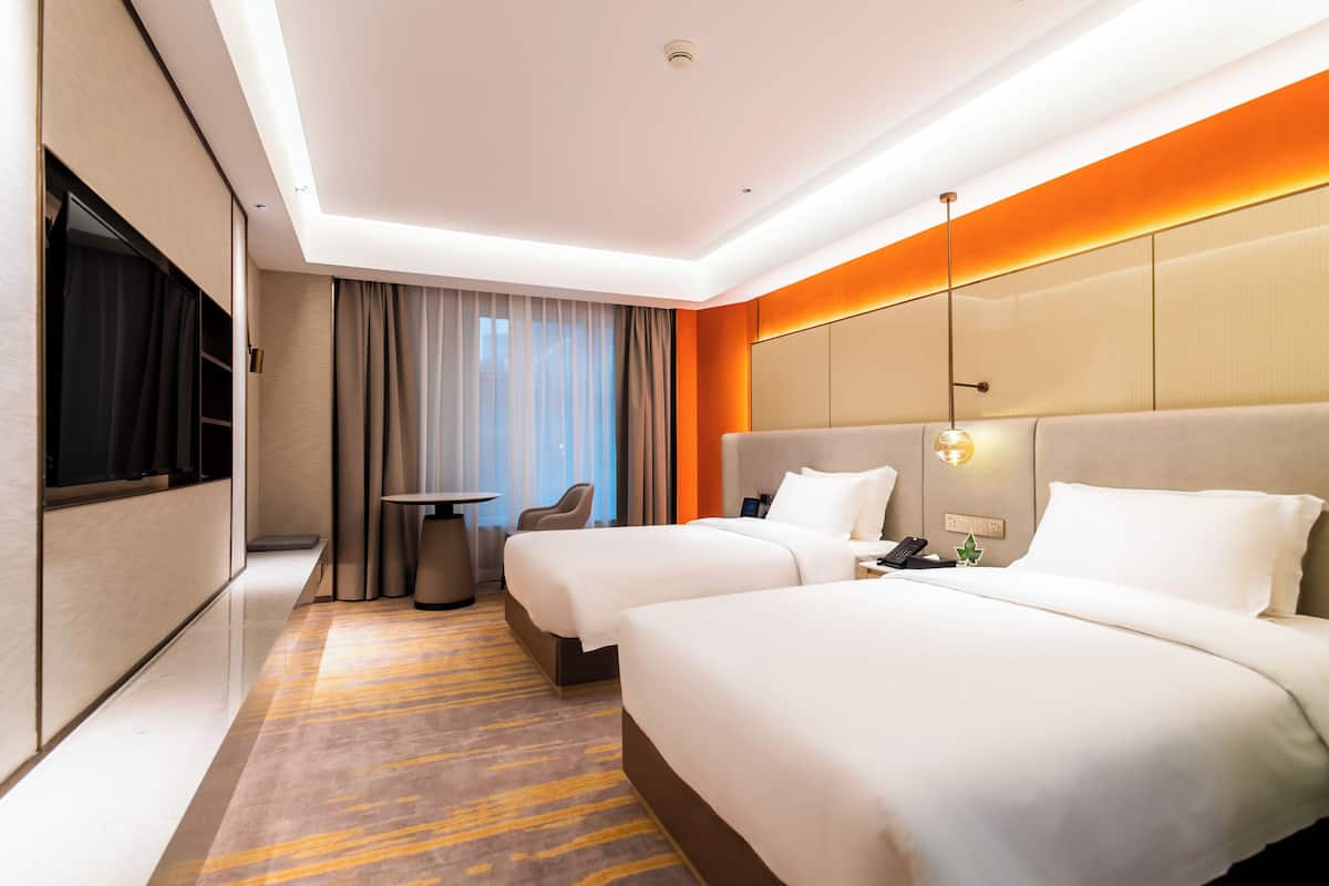Een hotelkamer met twee bedden, een bureau, een stoel en een televisie.