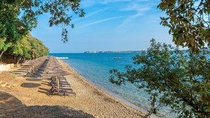 A beach with rows of sun loungers and umbrellas, clear blue sea, and a distant shoreline. - Valamar Tamaris Villas (Tar-Vabriga)