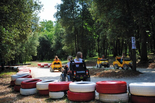 A dirt track with tires and vehicles, surrounded by trees. - Valamar Tamaris Villas (Tar-Vabriga)