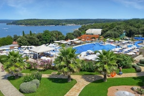 A resort with a large swimming pool, palm trees, and a view of the sea. - Valamar Tamaris Villas (Tar-Vabriga)