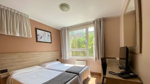 A hotel room with two beds, a desk with a computer and phone, a window with curtains, and a painting on the wall. - Somriu Hotel Vall Ski (Soldeu)