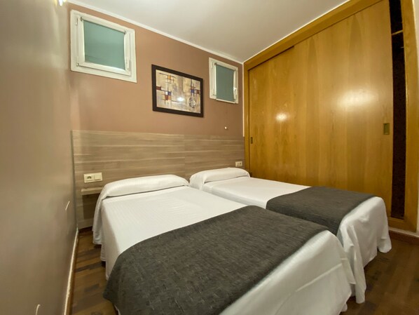 A hotel room with two beds, a wooden wardrobe, and a framed artwork on the wall. - Somriu Hotel Vall Ski (Soldeu)