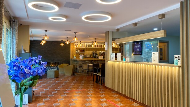 A hotel lobby with a reception desk, seating area, and a bar. - Somriu Hotel Vall Ski (Soldeu)