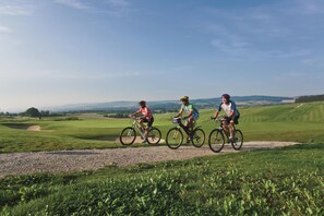 Tres ciclistas en un camino de grava con un paisaje rural al fondo.
