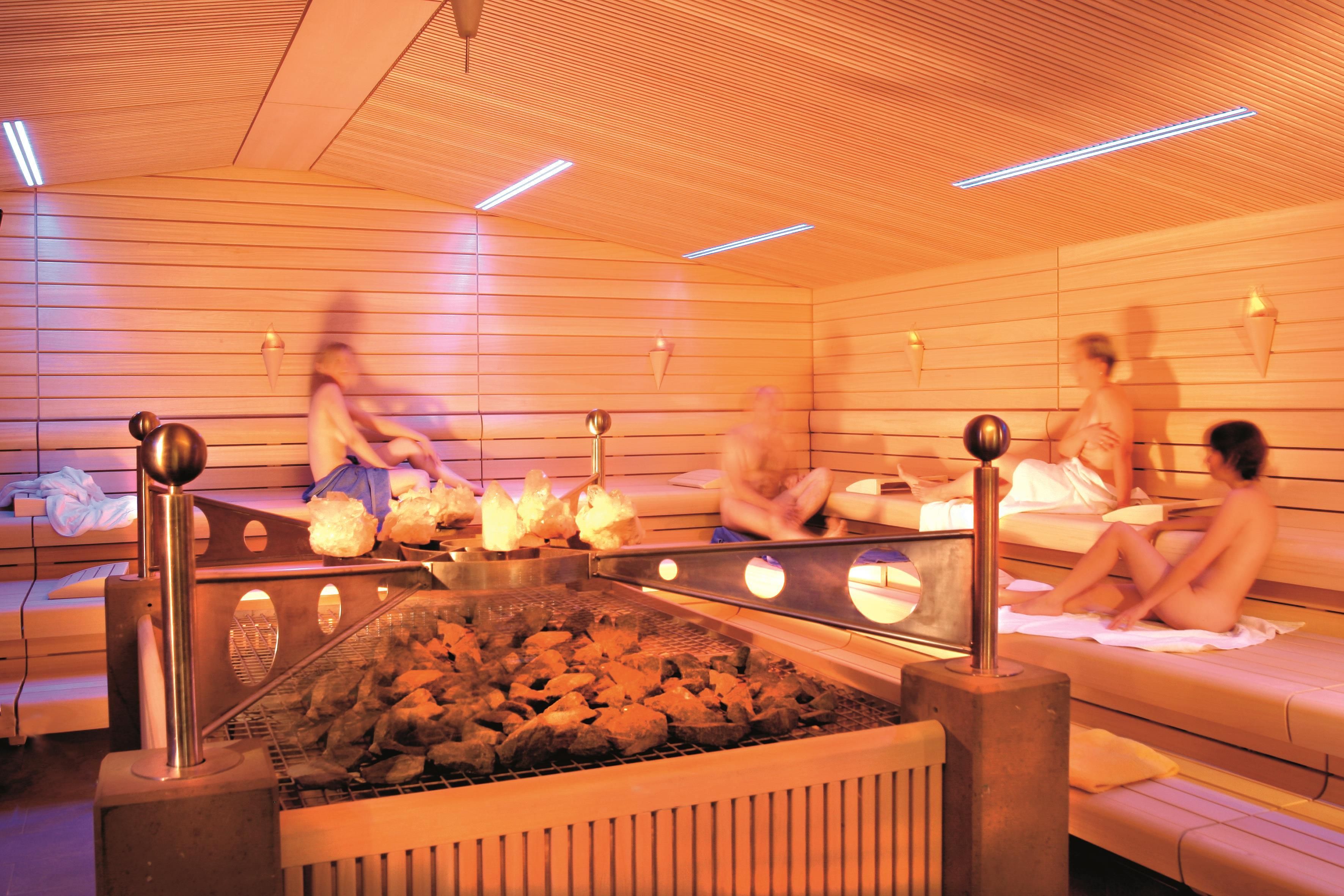 A sauna with wooden benches and a central heating element.