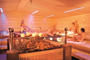 A sauna with wooden benches and a central heating element.