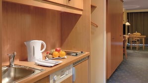 A compact kitchen with wooden cabinets, a sink, a kettle, and a fruit bowl.