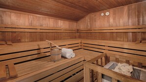 A sauna with wooden benches, a wooden bucket, and towels. - Best Western Aparthotel Birnbachhoehe (Bad Birnbach)