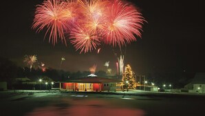 Un edificio con entrada iluminada en rojo, un árbol de Navidad y un suelo cubierto de nieve.