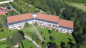 A large, modern building with a red roof, surrounded by green lawns and trees. - Best Western Aparthotel Birnbachhoehe (Bad Birnbach)
