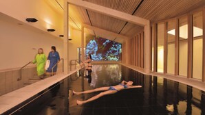 Zona de piscina con techo de madera, suelo de baldosas y una gran pantalla digital mostrando una imagen.