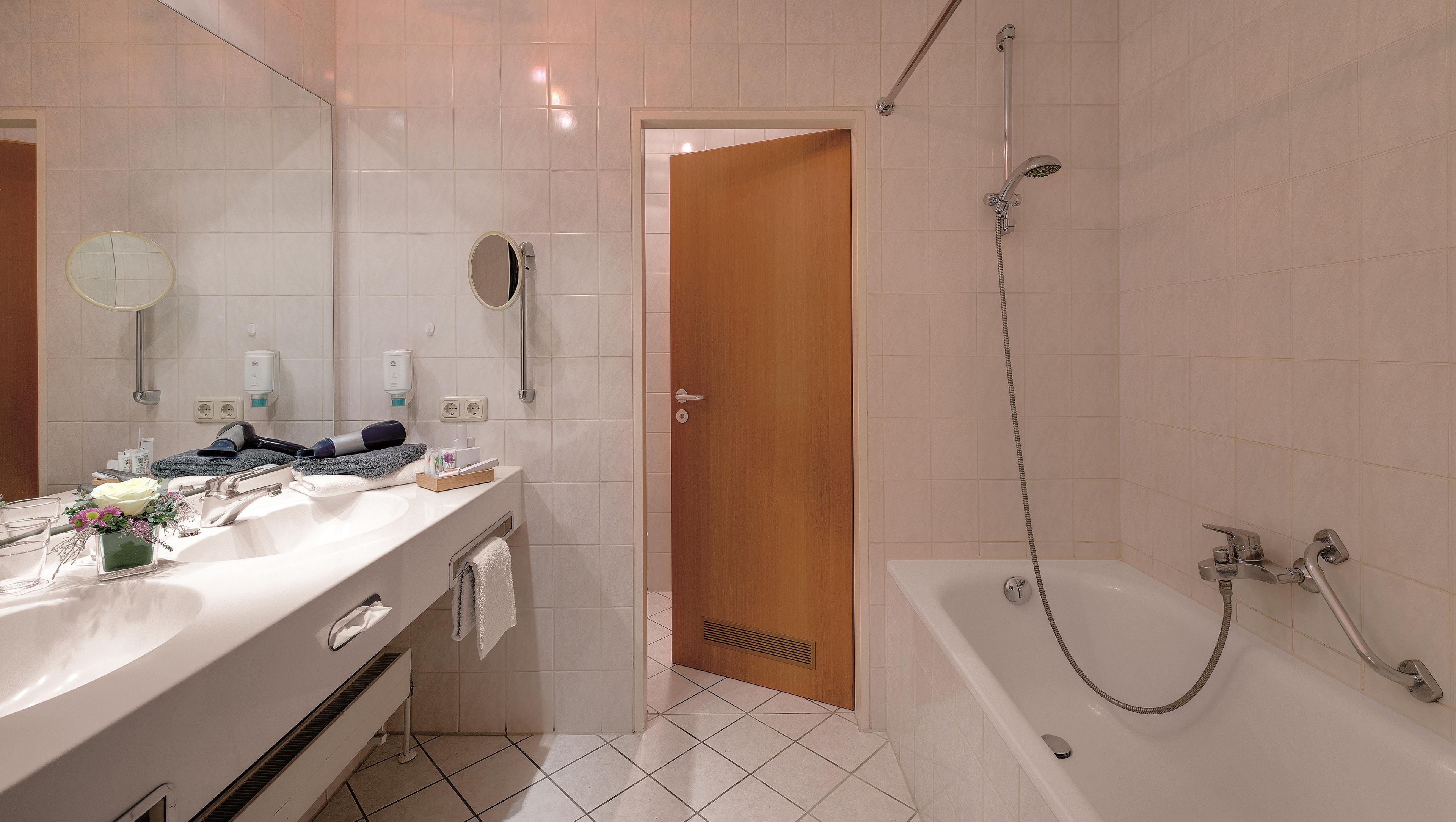 A modern bathroom with a bathtub, a shower, a vanity with a mirror, and a toilet.
