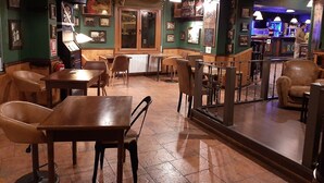 A restaurant interior with wooden tables and chairs, a bar area, and various framed pictures on the walls. - Hotel Comapedrosa (Arinsal)