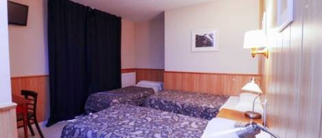 A hotel room with two beds, a desk, a chair, a lamp, and a picture on the wall.