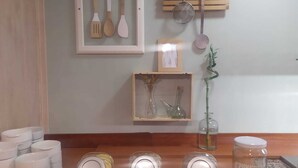 A kitchen counter with jars of condiments, a framed set of wooden utensils, and a hanging clothespin rack. - Hotel Comapedrosa (Arinsal)