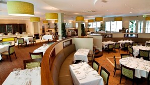 Un restaurante amplio con varias zonas de comedor, incluyendo una zona central con un banco curvo y varias mesas redondas.