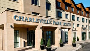 El exterior del Hotel Charleville Park, con una fachada moderna, grandes puertas de entrada y plantas en macetas al frente.