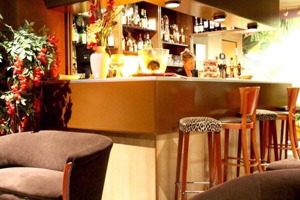 A bar area with a counter, stools, and a variety of bottles and glasses.