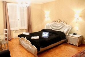 Een slaapkamer met een bed, nachtkastje, stoel en raam met gordijnen.