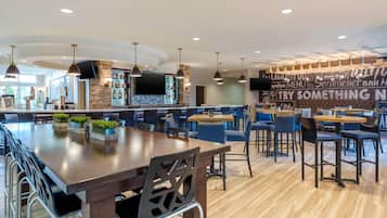 A modern bar area with a stone wall, wooden bar counter, and hanging pendant lights.