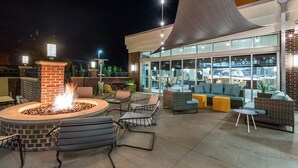 An outdoor patio area with a fire pit, seating, and a view of the building's interior. - Cambria Hotel Akron - Canton Airport (Uniontown)
