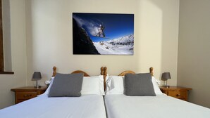 A double bed with two pillows, wooden headboard, bedside tables with lamps, and a painting of a snowy mountain scene. - Wuau! Apartaments Font del Poble (Ransol)
