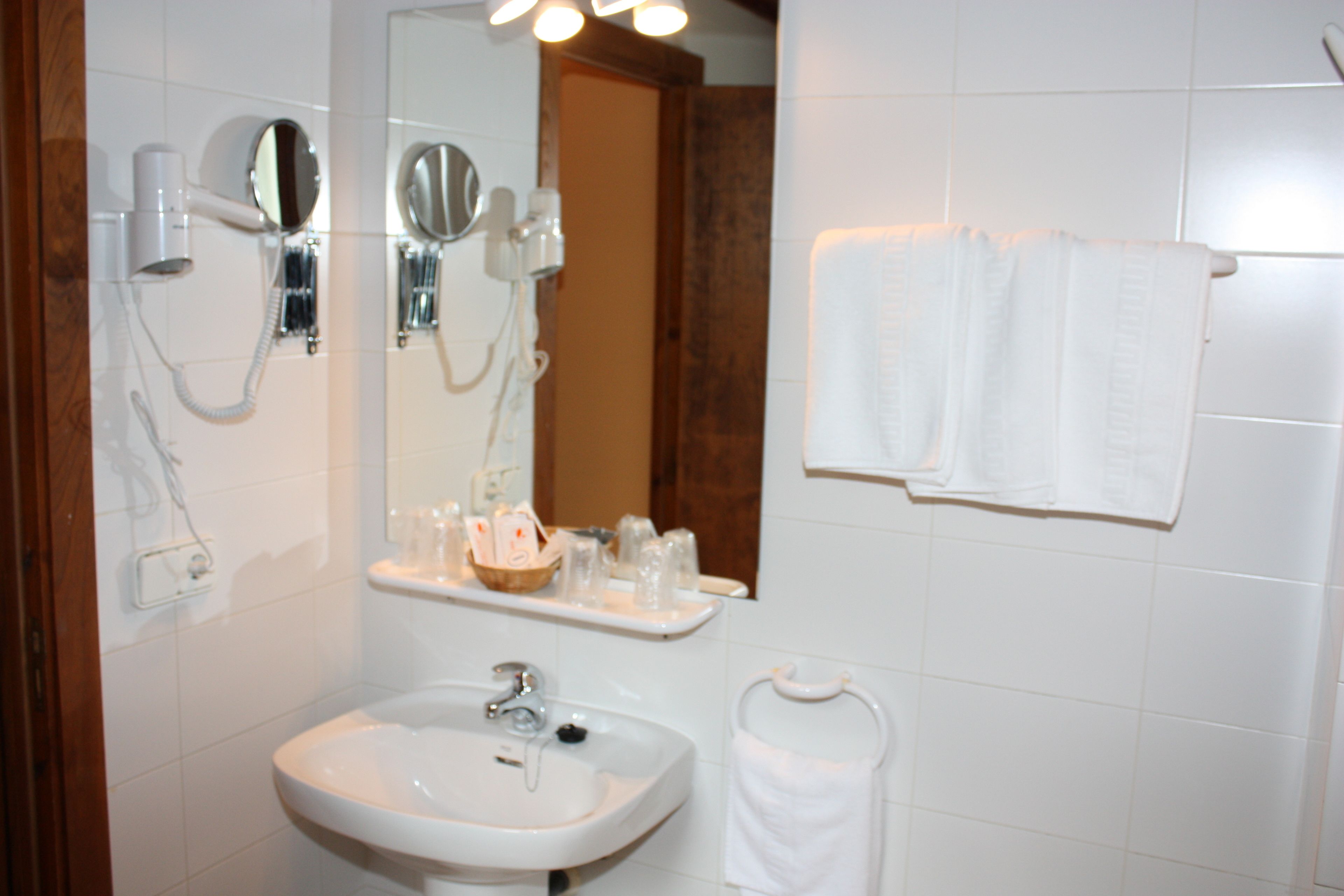 Een badkamer met een wastafel, spiegel, handdoekhouder en haardroger.