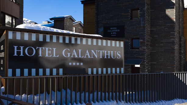 A sign for Hotel Galanthus with a modern stone building in the background. - Wuau! Hotel Galanthus & Spa (Soldeu)