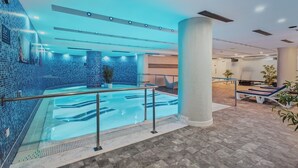 An indoor swimming pool with a tiled wall, a large pillar, and lounge chairs. - Wuau! Hotel Galanthus & Spa (Soldeu)