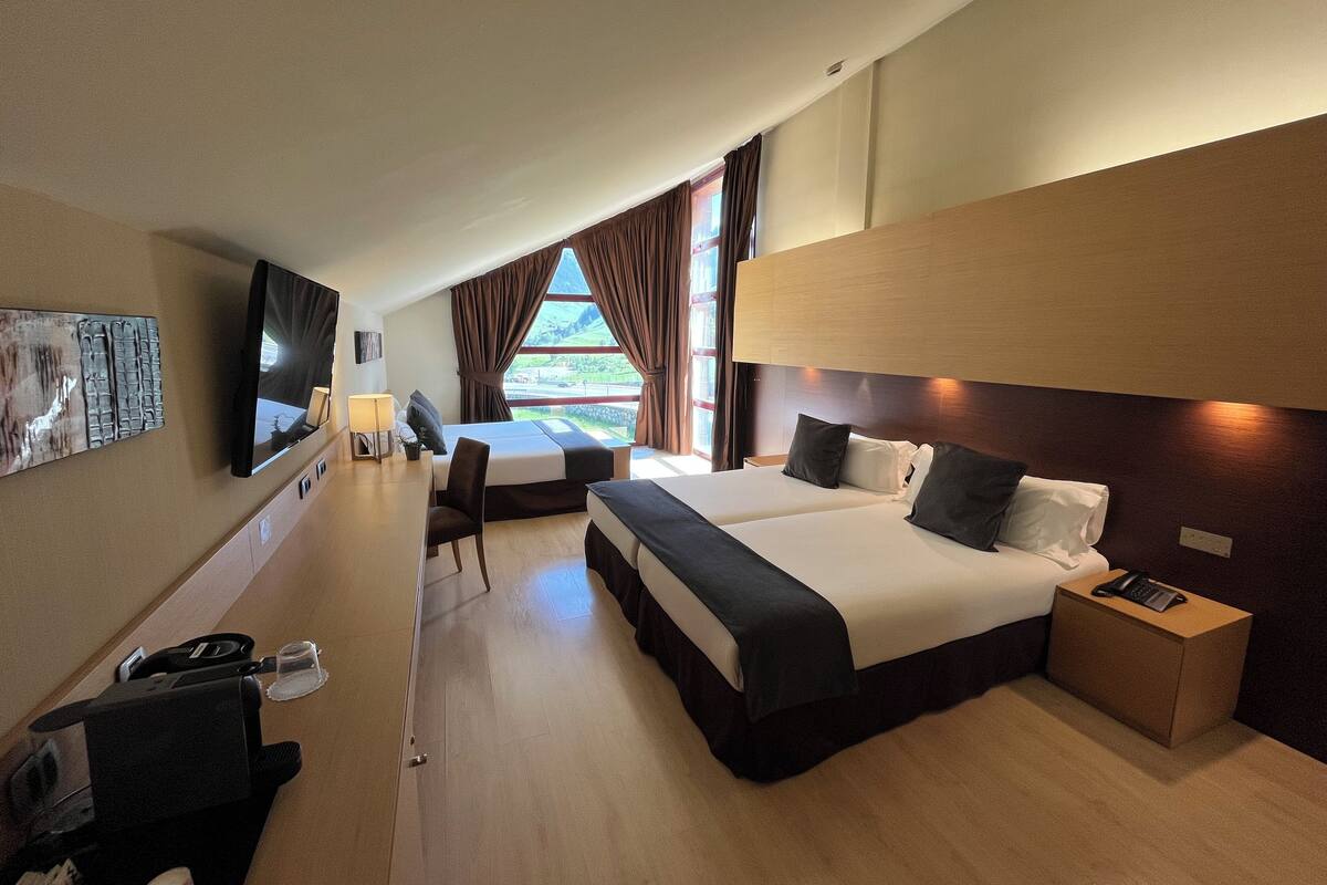 Une chambre d’hôtel avec un grand lit, un bureau avec un téléphone, une chaise et un téléviseur fixé au mur.