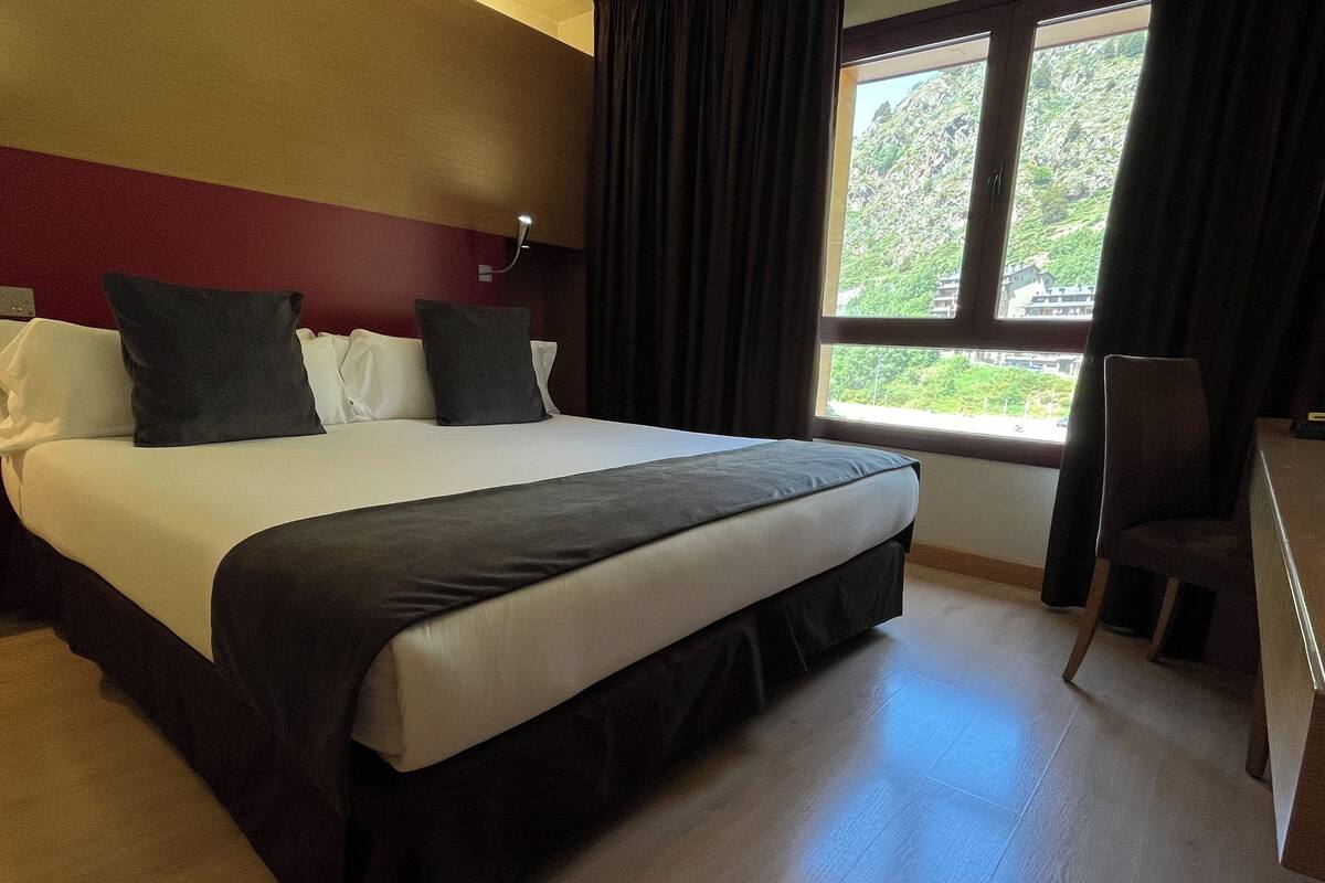 Une chambre d’hôtel avec un grand lit, un bureau et une chaise.