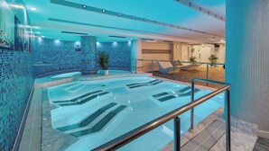 A modern indoor pool area with a clear water feature, a seating area, and a reception desk. - Wuau! Hotel Galanthus & Spa (Soldeu)