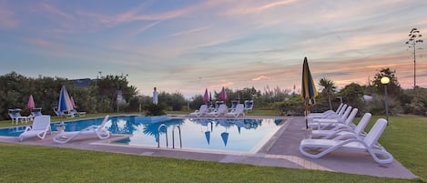 Una piscina techada, una piscina al aire libre de temporada, sombrillas