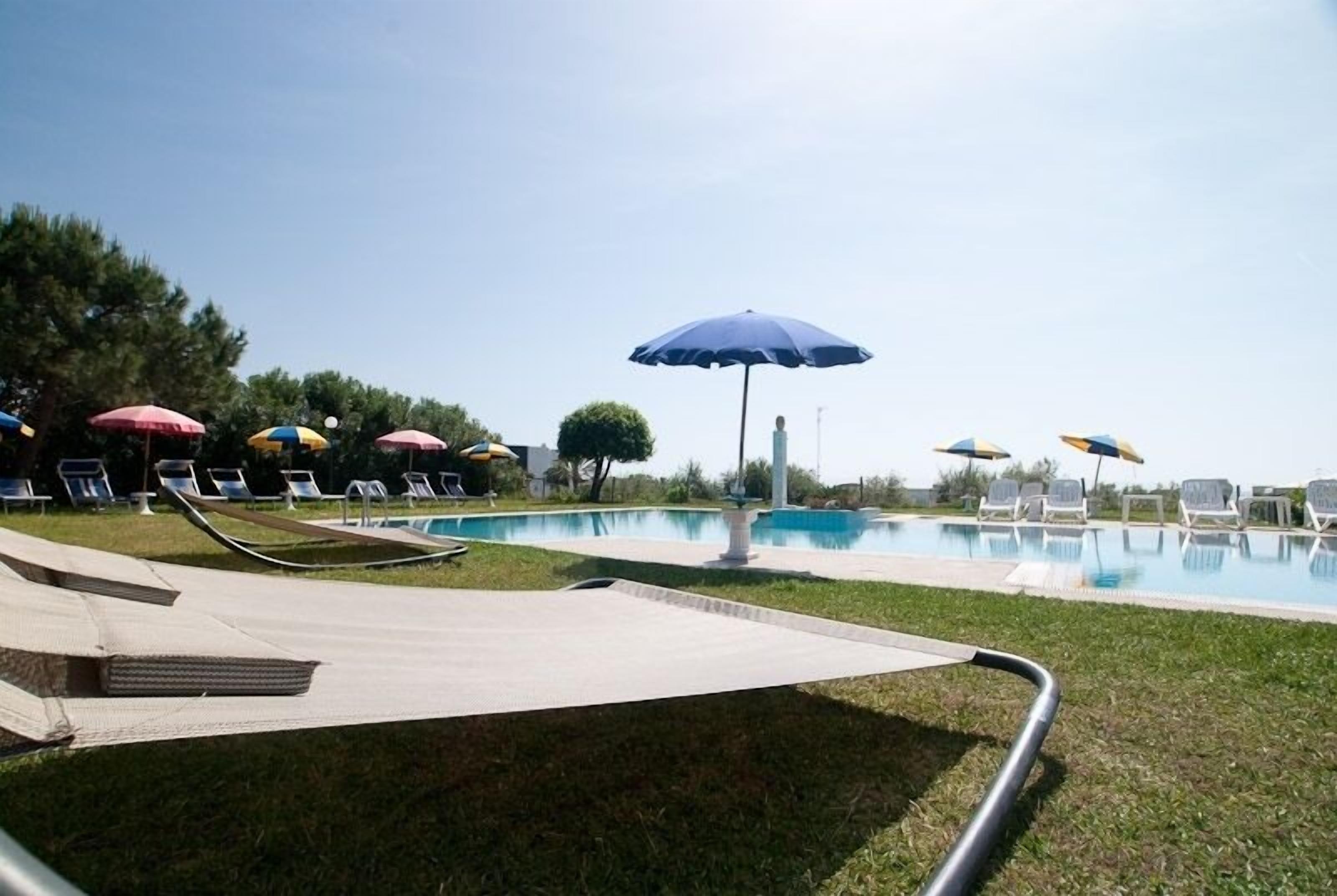 Zona de piscina con sillones de playa y sombrillas.