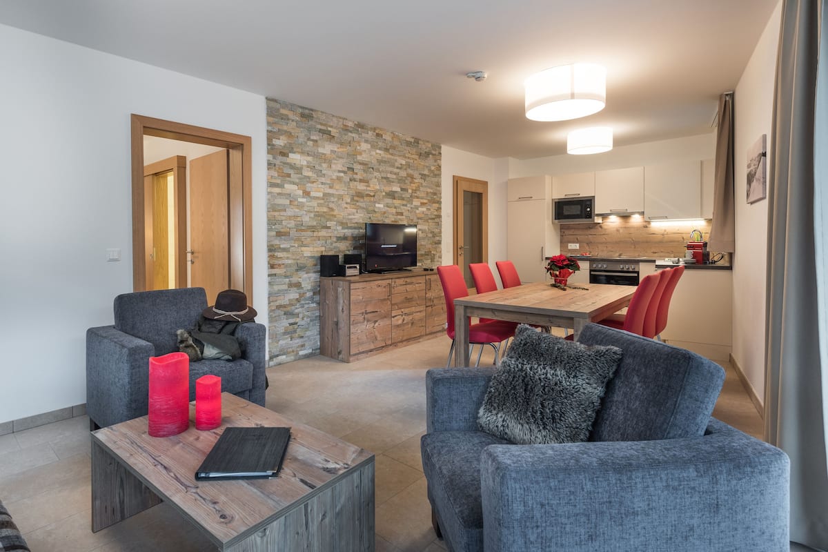 A modern living room with a fireplace, a dining area, and a kitchen.